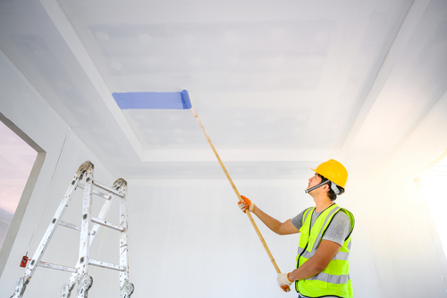 professional house painting contractor painting a ceiling blue with a extended roller brush