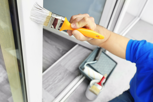 professional house painting contractor painting window trim on the exterior of a home