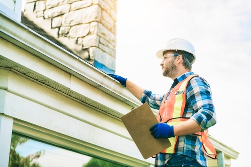 man inspecting a roof for estimating roof replacement and repair services