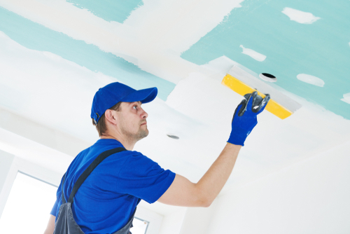 professional house painting contractor spackling a ceiling